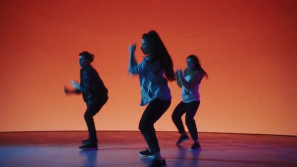Tre dansare uppträder framför färgad digital skärm — Stockvideo