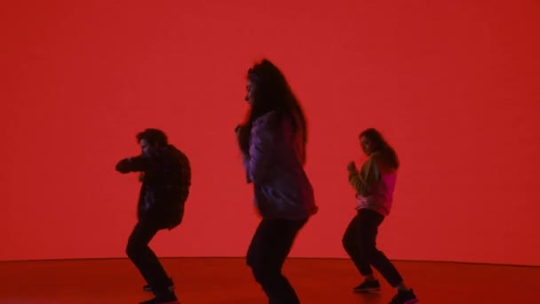Три танцюристи перед кольоровим цифровим екраном — стокове відео