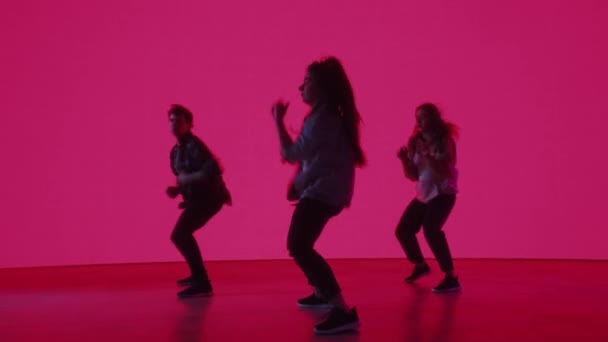 Три танцора выступают перед цветным цифровым экраном — стоковое видео