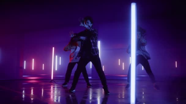 Три танцора выступают перед экраном цифрового неонового гаража — стоковое видео
