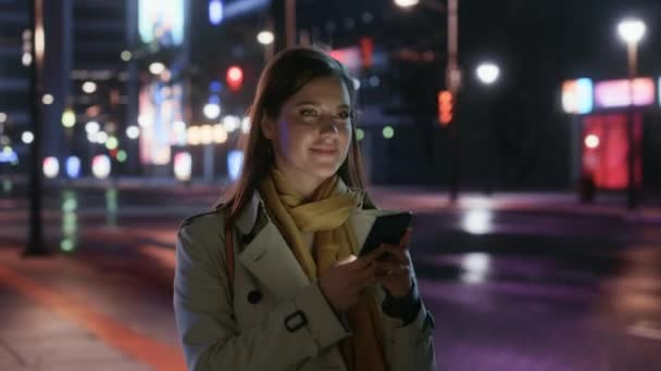 Vrouw wandelen in de stad met smartphone 's nachts — Stockvideo