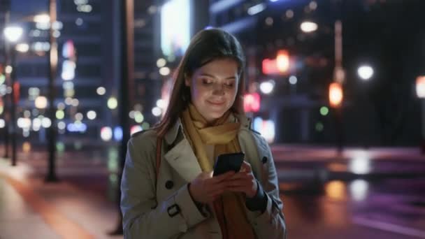 Vrouw wandelen in de stad met smartphone 's nachts — Stockvideo