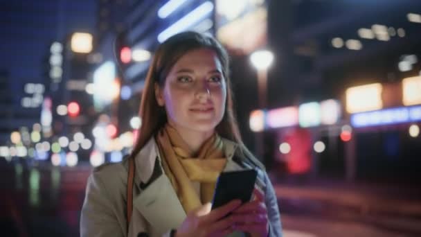 Frau läuft nachts mit Smartphone durch die Stadt — Stockvideo