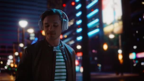 Людина в навушниках ходить у нічному місті — стокове відео