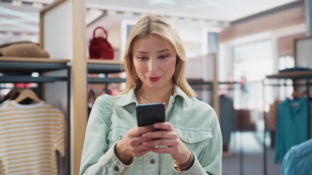 Kobieta klient ze smartfonem w sklepie odzieżowym — Wideo stockowe