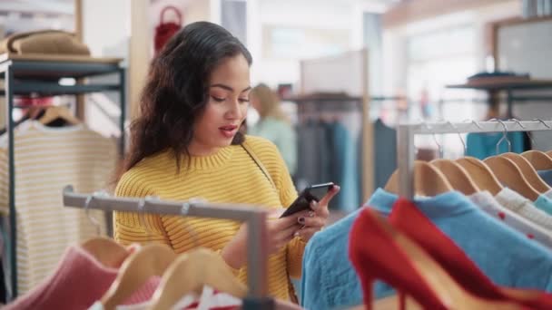 Cliente feminino com smartphone na loja de roupas — Vídeo de Stock