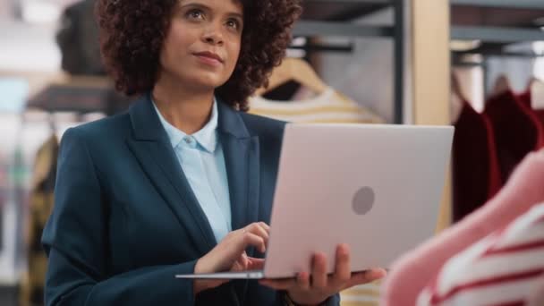 Verkäuferin im Bekleidungsgeschäft arbeitet mit Laptop — Stockvideo