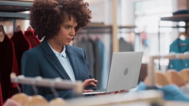 Assistante de vente de magasin de vêtements travaillant avec un ordinateur portable — Video