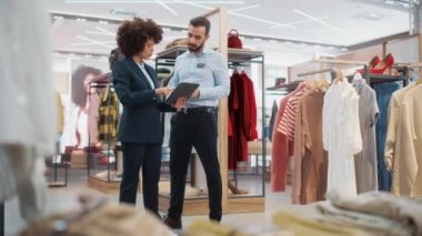 Tablet 'le çalışan iki giyim mağazası satış asistanı.