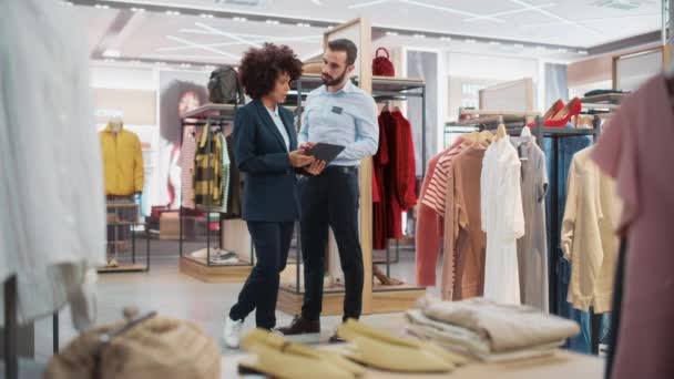 Asistentes de ventas de dos tiendas de ropa que trabajan con Tablet — Vídeo de stock