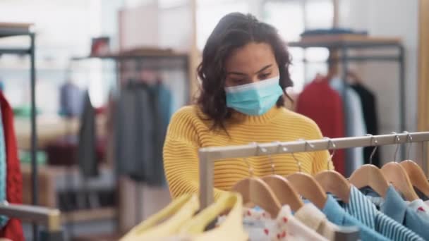 Vrouwelijke klant in het gezicht masker in de kledingwinkel — Stockvideo