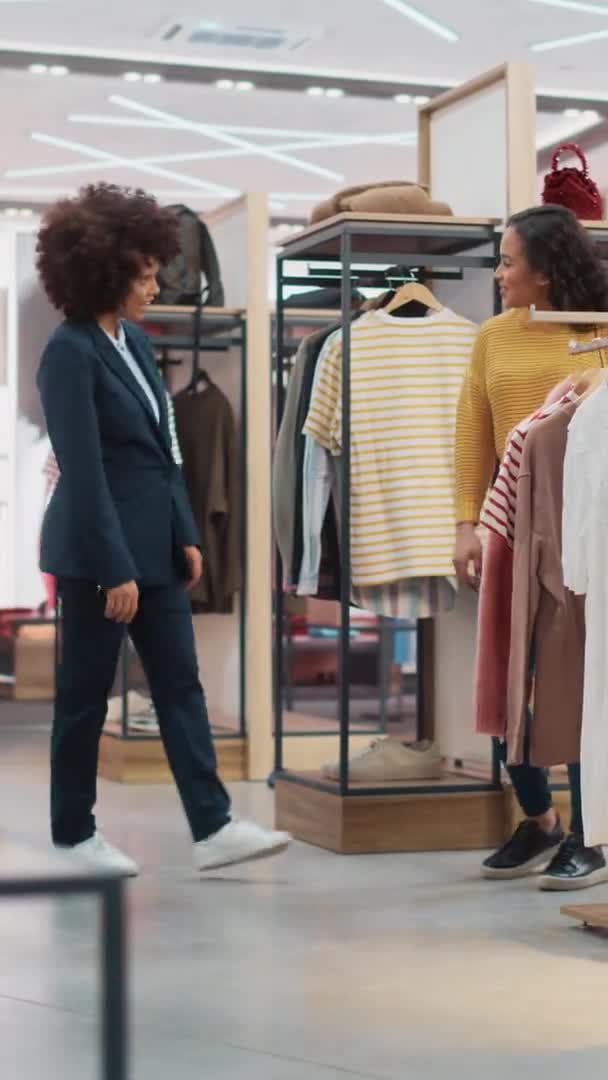 Cliente femenino de metraje vertical con asistente de ventas de tienda de ropa — Vídeos de Stock