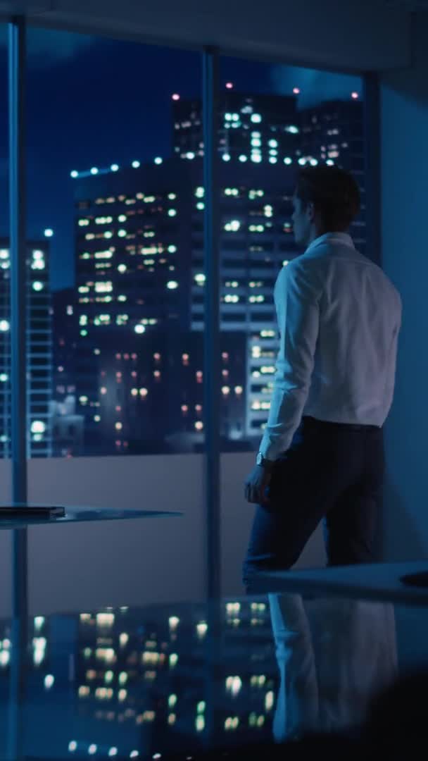 Függőleges portré Üzletember kinézett az ablakon éjszaka — Stock videók