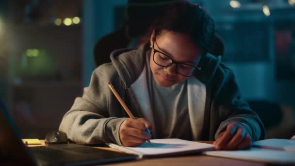 Młoda dziewczyna robi prace domowe w notatniku w domu — Wideo stockowe