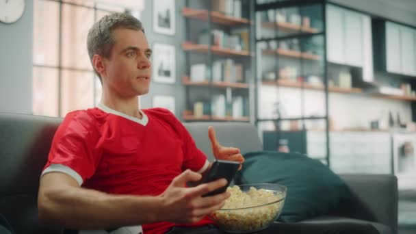 Man kijkt TV thuis het beste met Smartphone — Stockvideo