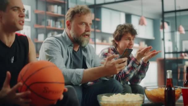 バスケットボールファンスマートフォンでテレビベットを見る — ストック動画