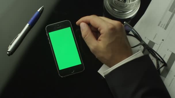 Homme d'affaires utilisant un téléphone portable avec écran vert qui repose sur la table. Vue du dessus . — Video