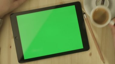 Tablet ile yeşil perde ahşap bir masa üzerinde döşeme.