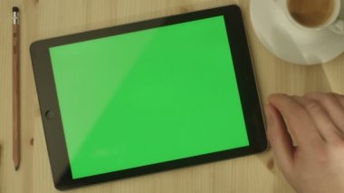 Tablet ile yeşil perde ahşap bir masa üzerinde döşeme.