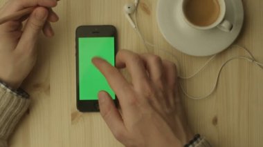 Telefon ile yeşil perde ahşap bir masa üzerinde döşeme.