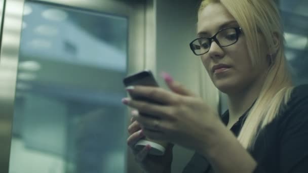 Üzletasszony, kávét, és a lift a mobiltelefon használata — Stock videók