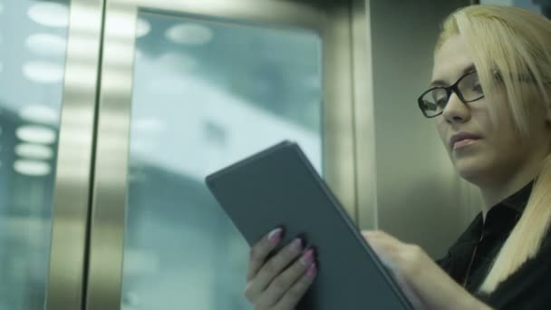 Hübsche Geschäftsfrau mit Tablet-PC im Aufzug — Stockvideo