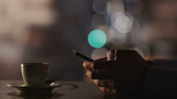 Az ember gépelés egy üzenet kávéház esti időpontban mobiltelefon használata.