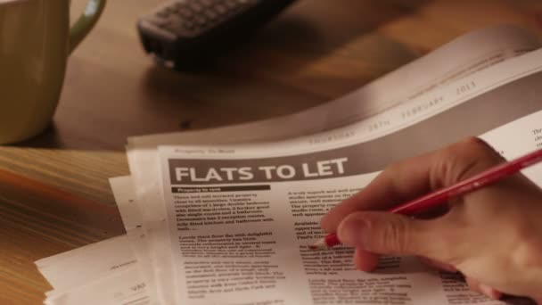 Man Marking Advertisement of Flats in a Newspaper Using Red Pencil. — Stock Video