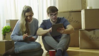 Genç çift telefon kullanarak ve yeni ev eğlence için Tablet olduğunu.