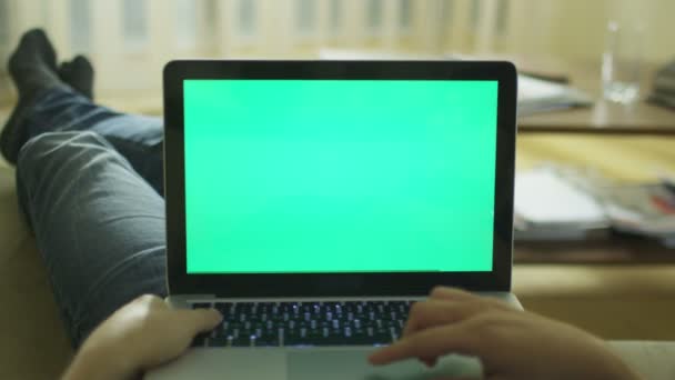 Posa sul divano a casa utilizzando il computer portatile con schermo verde . — Video Stock