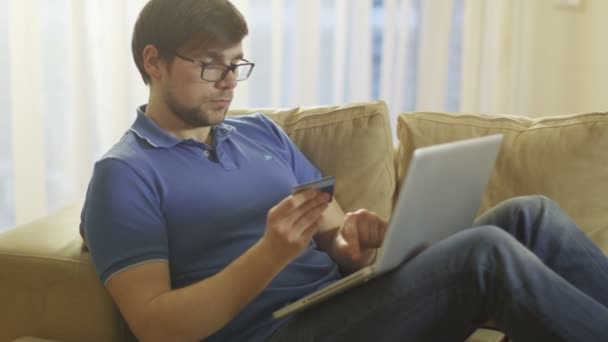 Man op de Bank te leggen en met behulp van Laptop voor Online winkelen thuis — Stockvideo