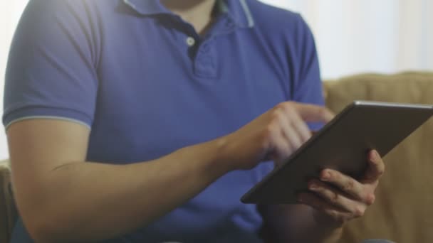 Homem sentado no sofá e usando Tablet — Vídeo de Stock