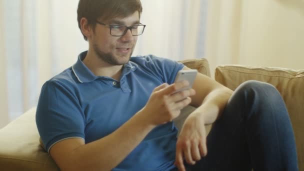 Человек сидит на диване и видео-чат по телефону . — стоковое видео