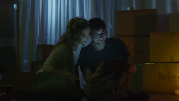 Pareja está viendo vídeo en la tableta por la noche en casa — Vídeo de stock