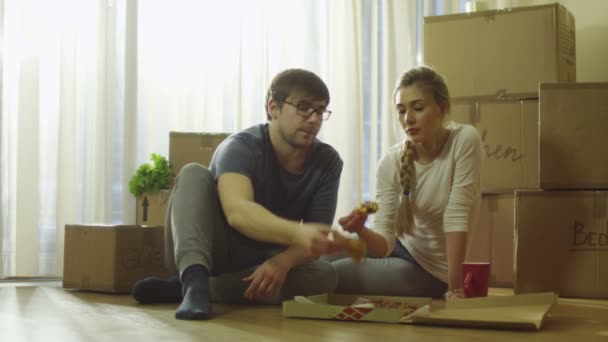 Пара ест пиццу в новом доме после переезда — стоковое видео