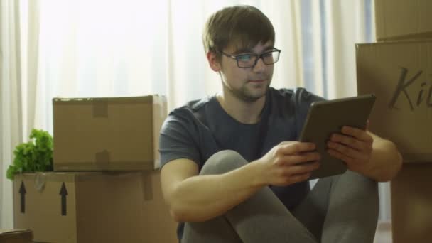 Человек, использующий планшет в новом доме после переезда — стоковое видео
