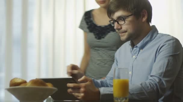 Пара читает новости на планшете за завтраком — стоковое видео