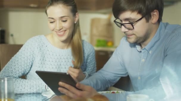 Пара использует планшет дома на кухне — стоковое видео