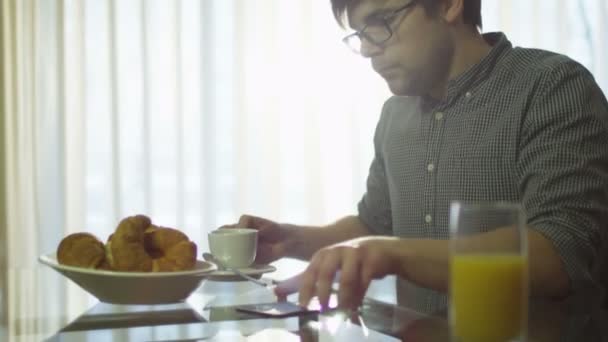 Ο άνθρωπος έχει ένα πρωινό και χρησιμοποιώντας το τηλέφωνο στο σπίτι — Αρχείο Βίντεο