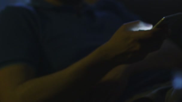 Man tar telefonen från bordet för att skriva ett meddelande på natten — Stockvideo