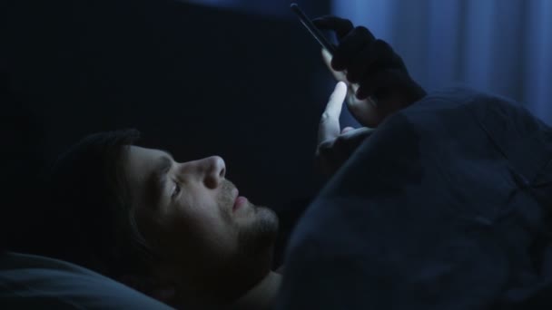 Mannen är med telefonen i sängen — Stockvideo