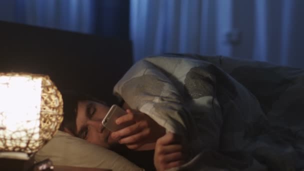 Человек, использующий телефон перед сном и выключение ночного света — стоковое видео