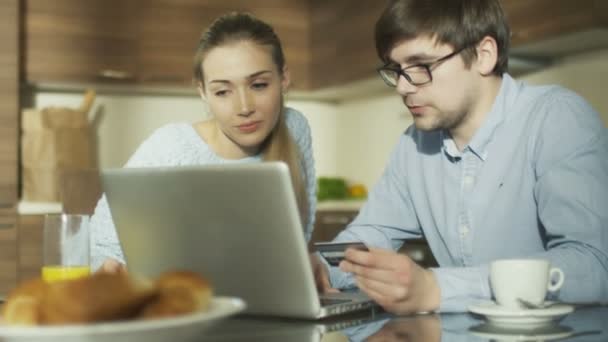 Пара использует ноутбук для покупок в Интернете на дому — стоковое видео