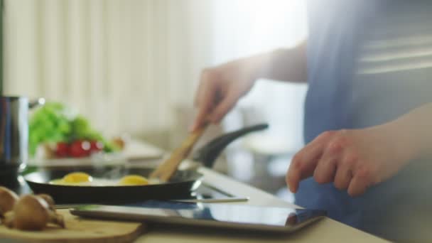 Чоловік використовує планшетний ПК під час приготування їжі — стокове відео