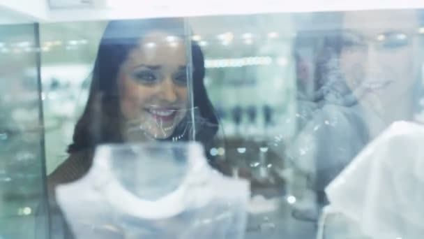 Duas meninas estão olhando para a vitrine da loja de jóias. Vista através de vidro . — Vídeo de Stock