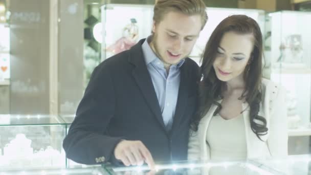 Молодая пара в ювелирном магазине смотрит на дисплее Windows — стоковое видео