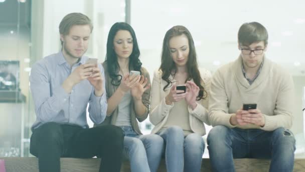 Groep tieners gebruiken mobiele telefoons in winkelcentrum — Stockvideo