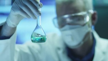 Bilim adamı bu durumda koruyucu gözlük teftiş kimyasal reaktifler şişesi içinde olduğunu. Yakın çekim.