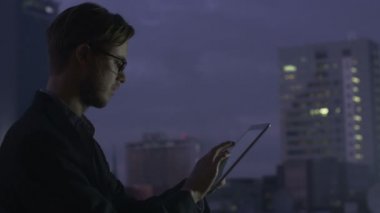 Genç işadamı kullanarak Tablet pencere yanında akşam olduğunu.