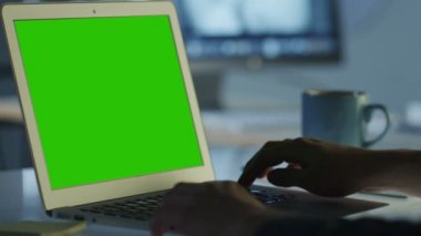 Yazılımcı ofisinde Mock-up için yeşil ekranlı dizüstü bilgisayarda çalışan